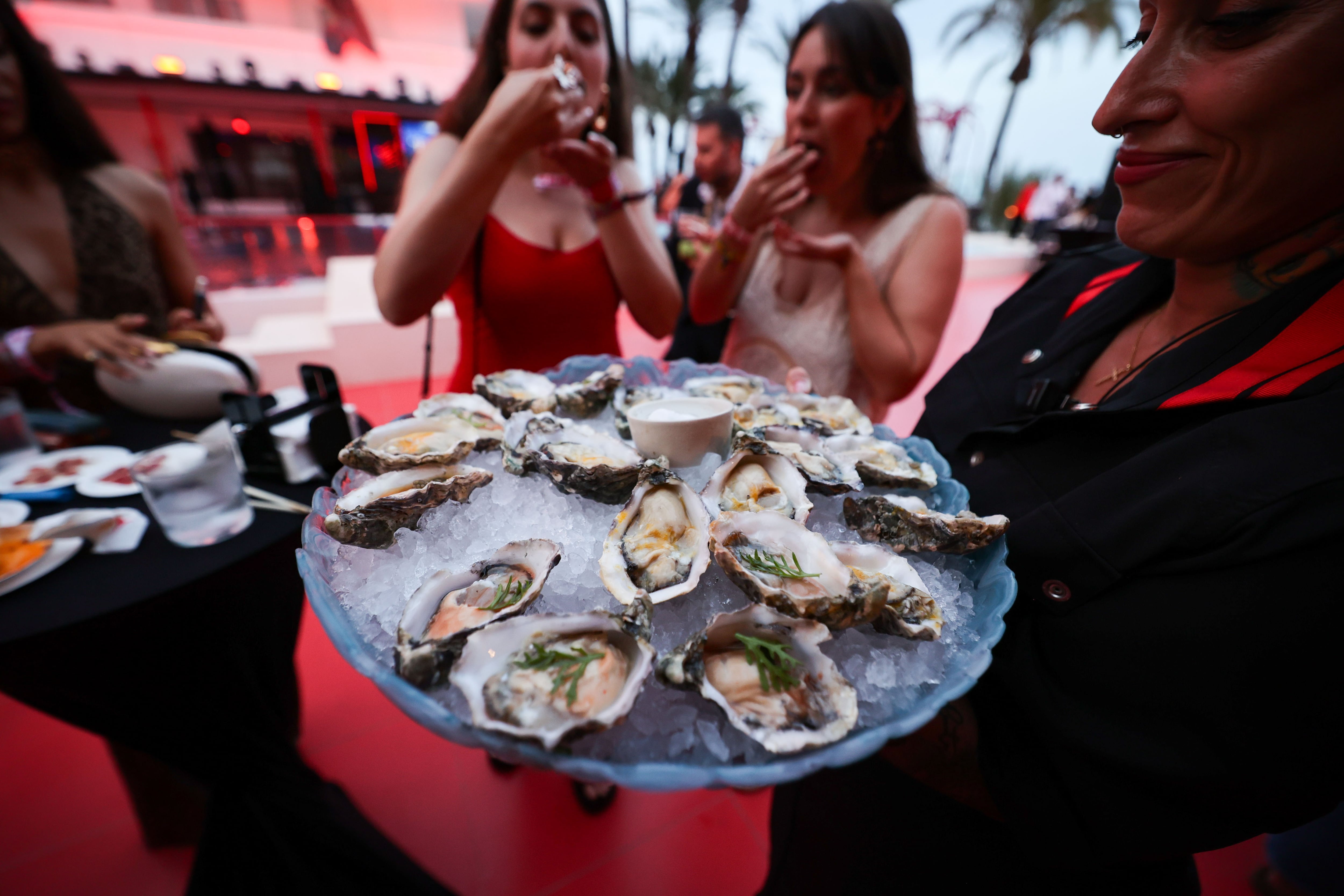 Invitadas a la fiesta de presentación del hotel de cinco estrellas The Unexpected Ushuaïa degustan ostras de su Oyster & Caviar Bar, a principios de junio.