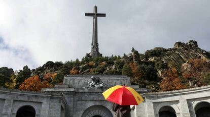 Una mujer sostiene un paraguas con los colores de la bandera de España en El Valle de los Caídos.