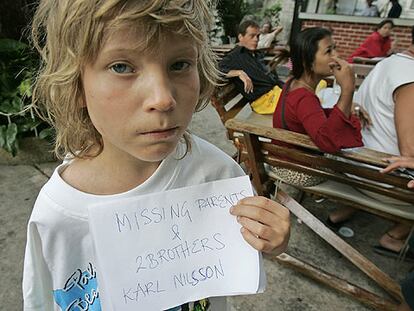 El niño sueco Karl Nilsson, en Phuket, con un cartel en el que puede leerse: "Padres y dos hermanos desaparecidos".