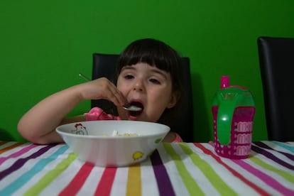 Sira cena sopa de fideos mientras ve dibujos animados. Su padre, Yovani, permanece a su lado para vigilarla y ayudarla si lo necesita.