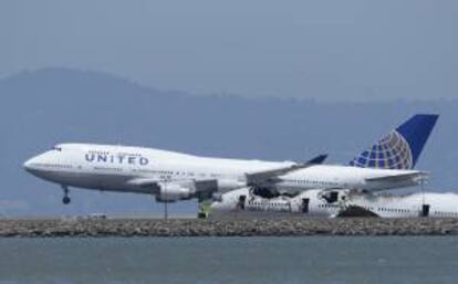 Un avión de United Airlines despega el 08 de julio de 2013, cerca de los restos del vuelo 214 de Asiana Airlines en el Aeropuerto Internacional de San Francisco (California, EE.UU.).