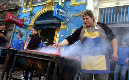 En Argentina, la cercanía de una cancha de fútbol la indican los cánticos de los hinchas y el humo de las parrillas donde se hace chorizo criollo a la brasa. Se sirve en pan con chimichurri. Como la que hace el hombre de la foto en las cercanías del campo del Boca. Grasa sabrosa para gritar "¡gol!".