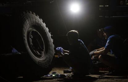 Dos mecánicos trabajan bajo un camión de su equipo en el campamento la carrera en Villa Carlos Paz (Argentina). La primera etapa ha sido cancelada por razones de seguridad debido a las fuertes lluvias.