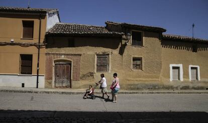 Dos mujeres pasean junto a una niña por Paredes de Nava.