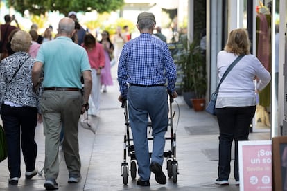 Personas mayores pasean por una calle de Sevilla.