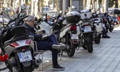 Una persona, asseguda en un banc, rodejada de motos.