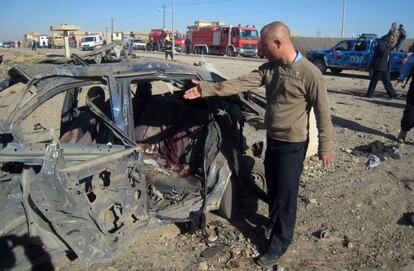 Un hombre, ante un coche destrozado por una bomba en Kirkuk.