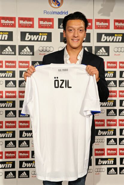 Özil posa con la camiseta del Real Madrid tras su presentación.
