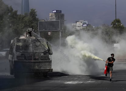 Un manifestante rocía un extintor contra un tanque de agua de la policía durante el estallido social.  En Santiago (Chile), en octubre de 2019.