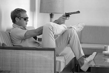 Steve McQueen, sentado no sofá de sua casa em Palm Springs (Califórnia) com uma pistola na mão, em maio de 1963.