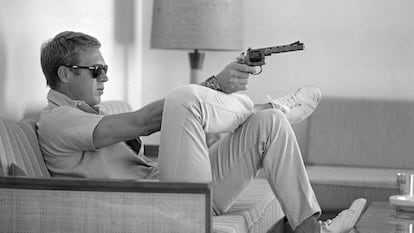 Steve McQueen, sentado no sofá de sua casa em Palm Springs (Califórnia) com uma pistola na mão, em maio de 1963.