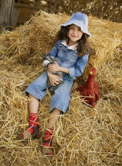 <b>Olivia</b>, con gorro de 'patchwork' vaquero de Bonpoint, cazadora vaquera de C&A, blusa de flores de Piupiuchick, pantalón ancho vaquero de Finger in the Nose, calcetines de Caramel Baby & Child, zuecos de ante y piel de Pisamonas y peluche de gallina de Jellycat.