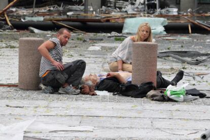 Un hombre y una mujer atienden a un herido en el lugar del atentado.