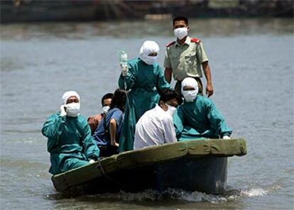 Personal médico transporta al hospital a un hombre, de blanco, sospechoso de neumonía, en Haiku (China).