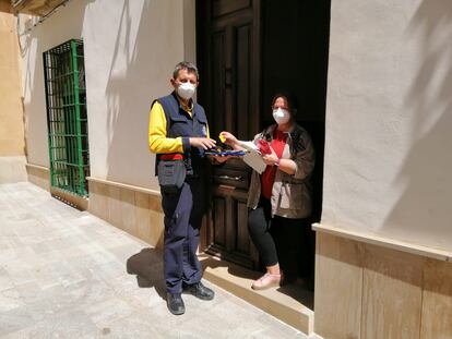 El cartero rural Miguel Ángel Méndez cobra un recibo de luz a una vecina de Bedmar (Jaén).