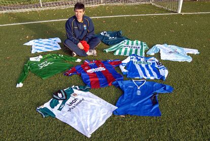 Juanito posa en el campo del Narón, su actual club, con las camisetas de sus antiguos equipos.