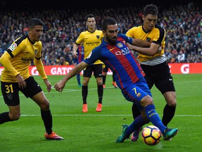 Arda Turan (centro) del Barcelona es presionado por Diego Llorente (derecha) del Málaga.