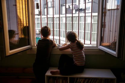 Two siblings look out their bedroom window during the lockdown in Madrid.