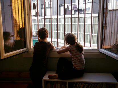 Two siblings look out their bedroom window during the lockdown in Madrid.