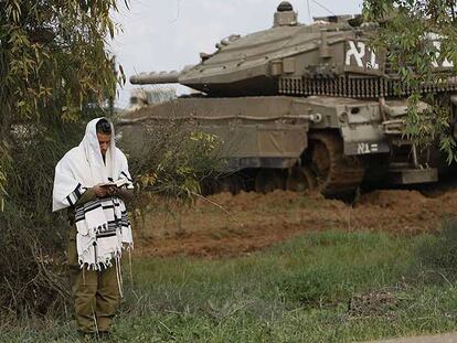 Un soldado israelí reza junto a un carro blindado en el despliegue del Ejército cerca de la frontera con Gaza.