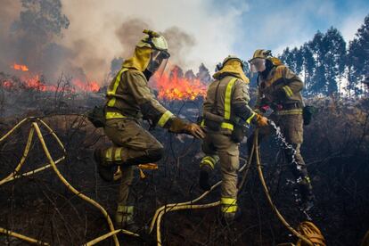 Tres bomberos trabajan en las operaciones de emergencias para apaciguar el incendio forestal en Rianxo (España), el 27 de marzo de 2019. El incendio fue decretado nivel dos por la proximidad a las viviendas de varios núcleos rurales afectados en los ayuntamientos de Dodro y Rianxo. Según las últimas estimaciones del Gobierno regional, el fuego arrasó más de 850 hectáreas.