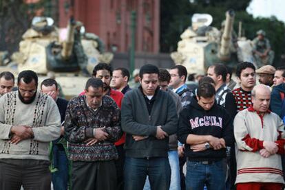 Un grupo de personas reza delante de los tanques en la plaza de La Libertad.