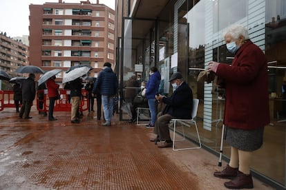 Decenes de persones esperen el seu torn per votar al poliesportiu Camp del Ferro, en Barcelona.