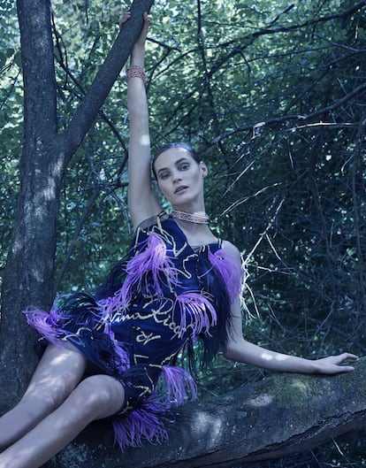 Vestido de gasa negra transparente bordado con plumas de Nina Ricci, collar de tela con cristales y brazalete, ambos de Swarovski. 