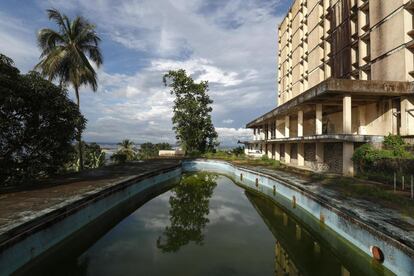 Vista de la piscina del antiguo Hotel Ducor en Monrovia, Liberia, el 1 de octubre de 2017. El hotel Ducor fue en su día el más prominente de África. Construido en el punto más elevado de Monrovia por el israelí Moshe Mayer en 1960, cerró sus puertas 29 años después tras haber sido el primer establecimiento hotelero de 5 estrellas en el continente. Frecuentado por políticos, diplomáticos y empresarios de toda África y extranjero, fue un ejemplo de los años prósperos que vivió en aquella época la África occidental. Sus instalaciones acogieron numerosas reuniones entre líderes africanos y numerosas anécdotas envuelven su historia, como una del dictador ugandés Idi Amin, de quien se dice que se zambulló en su piscina con pistola incluida. El Ducor fue usado tamibén como posicionamiento de tiro por los compatientes del ex presidente liberiano Charles Taylor durante el sitio de Monrovia por las fuerzas rebeldes en 2003. Desde entonces, una espesa vegetación rodea cada uno de los rincones de este edificio desértico de estilo art déco.