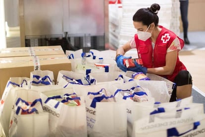 Una voluntaria prepara paquetes de alimentación básica en el almacén de la Cruz Roja en Barcelona.