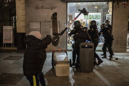 Un manifestante lanza un monopatín a un grupo de agentes antidisturbios en una calle del centro de Madrid.