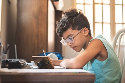 Un niño hace tarea en su casa desde un teléfono móvil.