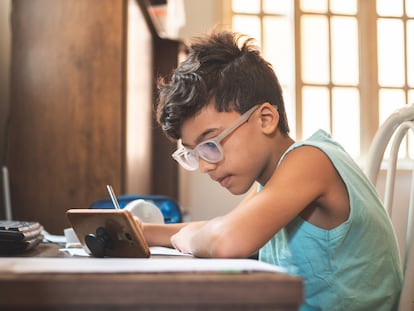 Un niño hace tarea en su casa desde un teléfono móvil.