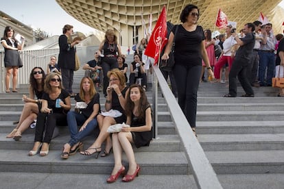 Un grupo de empleadas públicas, vestidas de negro en señal de luto, desayunan un bocadillo en la plaza de La Encarnación de Sevilla.