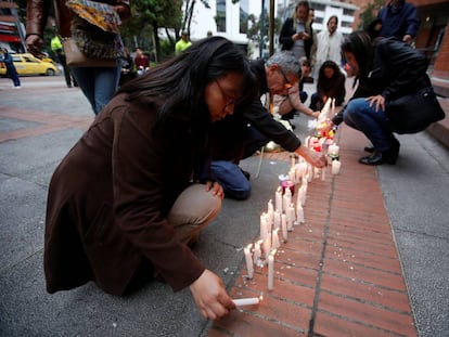 Varias personas encienden velas el d&iacute;a 18 en el centro comercial de Bogot&aacute; atacado la v&iacute;spera. 