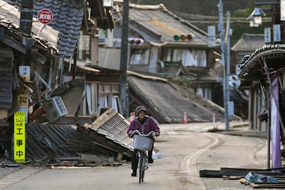 Una mujer monta en bicicleta entre los escombros de varias casas dañadas en la península de Noto, frente al mar de Japón, este martes. 