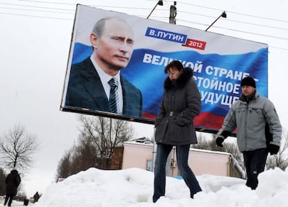 Dos personas frente a un cartel de Vladimir Putin en Moscú.