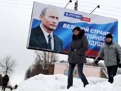 Dos personas frente a un cartel de Vladimir Putin en Mosc&uacute;.