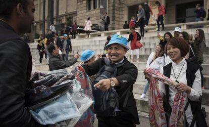 Una pareja de chinos compra ropa a un mantero delante del MNAC.