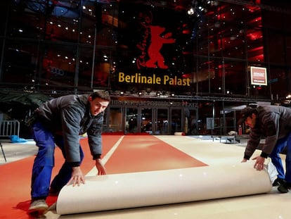 Dos trabajadores desenrollan la alfombra roja a la puerta del Palacio de la Berlinale.