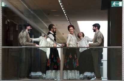 Varios miembros del coro charlan durante un descanso de la obra en los pasillos del teatro.