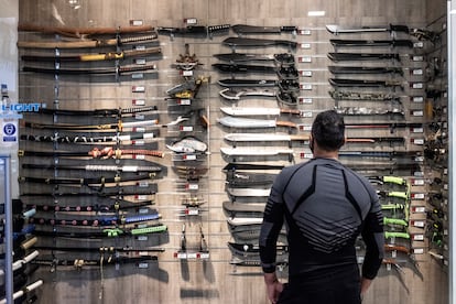 Un cliente ante un escaparate con machetes, dagas y cuchillos, en el centro comercial Islazul, en Carabanchel.