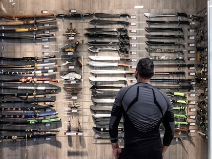 Un cliente ante un escaparate con machetes, dagas y cuchillos, en el centro comercial Islazul, en Carabanchel.