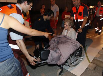 Una mujer es trasladada a un hospital por agentes sanitarios tras ser evacuada del centro.