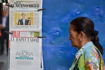 Una mujer camina cerca de periódicos en Cali (Colombia) donde anuncian el acuerdo de paz entre el Gobierno colombiano y las FARC.
