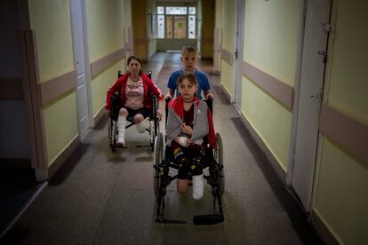 Yarik Stepanenko, de 11 años, empuja la silla de ruedas de su hermana gemela Yana en un hospital público en Lviv, Ucrania, el 12 de mayo de 2022.