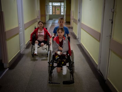 Yarik Stepanenko, de 11 años, empuja la silla de ruedas de su hermana gemela Yana en un hospital público en Lviv, Ucrania, el 12 de mayo de 2022.