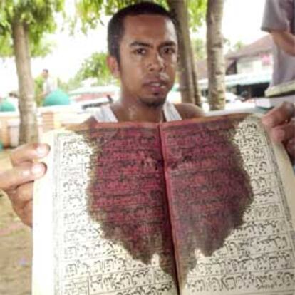 Un joven muestra un libro ensangrentado cerca de la mezquita de Kruesie, en Pattani, donde 35 rebeldes perdieron ayer la vida.