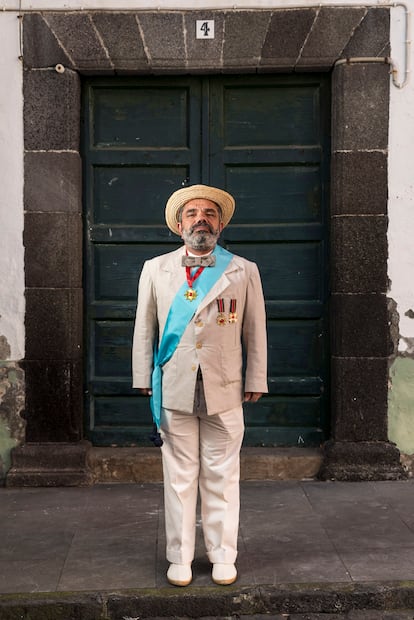 Quique Santacruz, actor palmero muy querido en la isla, con su versión del traje de indianos para hombres, con medallas y todo. Normalmente, la vestimenta masculina se compone de levitas o trajes completos que evocan el estilo de los antiguos emigrantes. Chalecos de algodón, guayaberas y sombreros Panamá son piezas clave del atuendo. Los complementos incluyen maletas, un reloj de bolsillo, puros y fajos de billetes. Las gafas de sol no son un añadido muy decimonónico, pero ayudan con el fuerte sol de mediodía y sobre todo para evitar el temible talco en los ojos. 