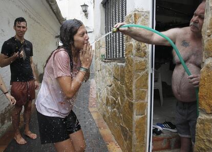 Un vecino limpia de tomate con una manguera a una participante de la Tomatina.